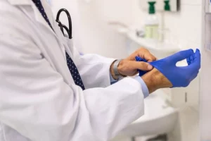 лікар одягає гумові руковиці