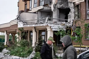Мешканці гуляють біля будинку, який постраждав від удару російського безпілотника, на фоні нападу Росії на Україну, на околиці Києва