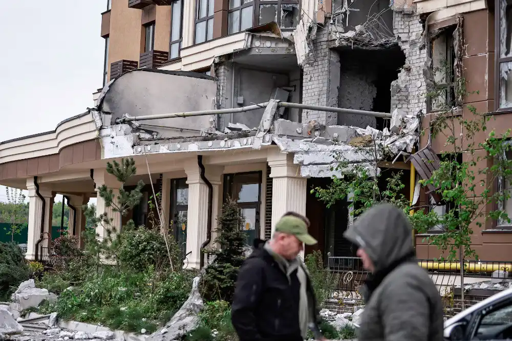 Мешканці гуляють біля будинку, який постраждав від удару російського безпілотника, на фоні нападу Росії на Україну, на околиці Києва