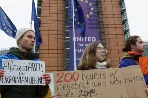 Люди тримають плакати під час демонстрації біля будівлі Європейської комісії на підтримку використання заморожених російських активів для фінансування України на тлі російської агресії проти України, Брюссель, Бельгія, 17 грудня 2025 року.