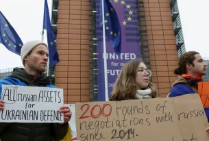 Люди тримають плакати під час демонстрації біля будівлі Європейської комісії на підтримку використання заморожених російських активів для фінансування України на тлі російської агресії проти України, Брюссель, Бельгія, 17 грудня 2025 року.
