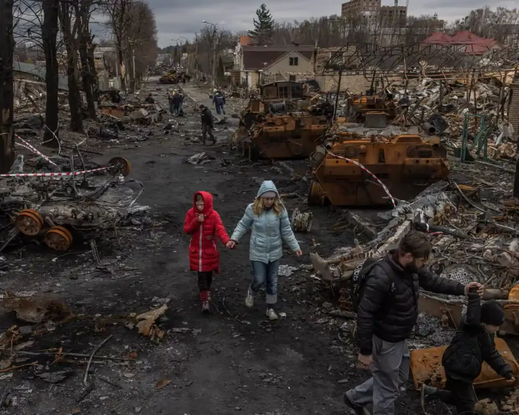 Родина з Бучі, міста на північ від Києва, проходить повз знищену російську військову техніку у квітні 2022 року