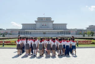 Зображення показує дітей, які розглядають будівлю в Пхеньяні, Північна Корея