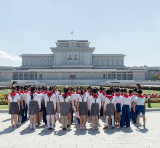 Зображення показує дітей, які розглядають будівлю в Пхеньяні, Північна Корея