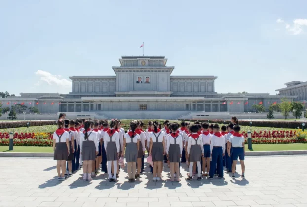 Зображення показує дітей, які розглядають будівлю в Пхеньяні, Північна Корея