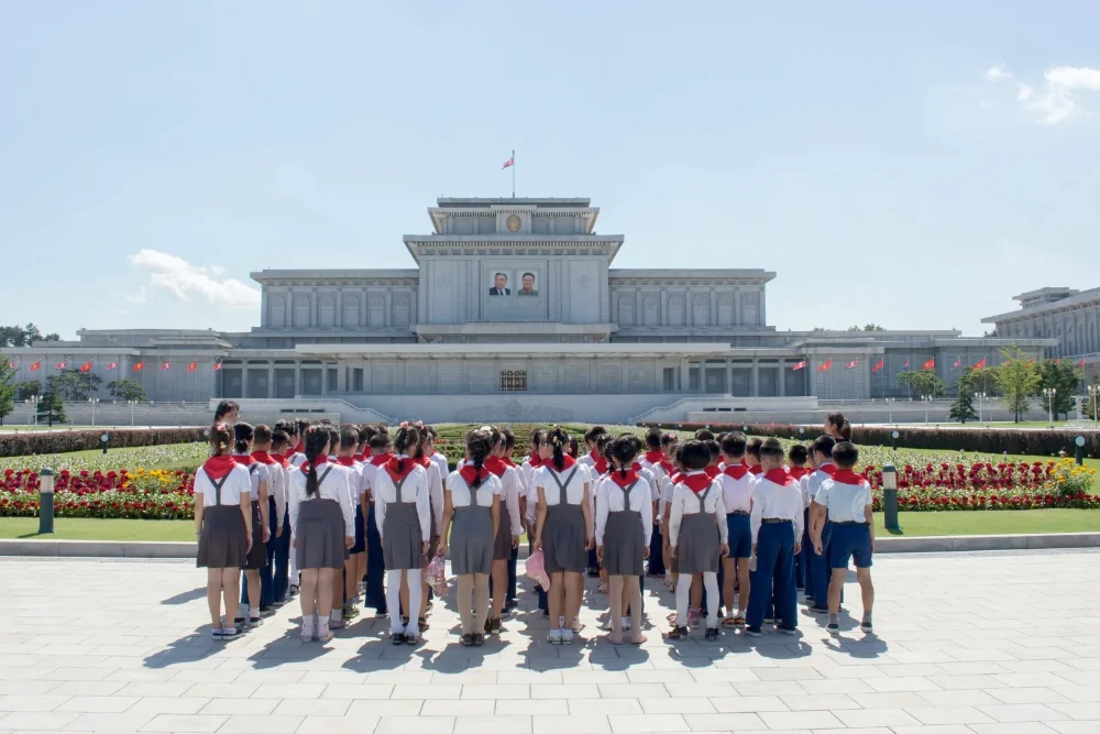 Зображення показує дітей, які розглядають будівлю в Пхеньяні, Північна Корея