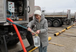 Жінка отримує питну воду, яку роздає влада в місті Донецьк у контрольованій Росією частині східної України, у четвер, 19 лютого 2026 року