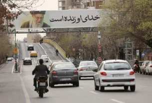 Люди їдуть біля банера покійного Верховного лідера Ірану аятоли Алі Хаменеї на вулиці, після того, як він був убитий внаслідок ізраїльських та американських ударів у суботу, в Тегерані, Іран, 2 березня 2026 року