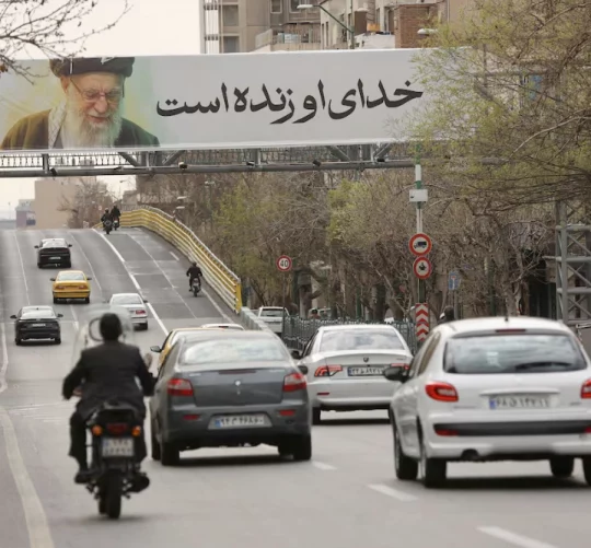 Люди їдуть біля банера покійного Верховного лідера Ірану аятоли Алі Хаменеї на вулиці, після того, як він був убитий внаслідок ізраїльських та американських ударів у суботу, в Тегерані, Іран, 2 березня 2026 року