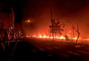 Мотоцикл проїжджає повз пожежу, що спалахнула вздовж бульвару Кухсар у Тегерані, Іран