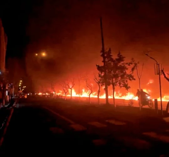 Мотоцикл проїжджає повз пожежу, що спалахнула вздовж бульвару Кухсар у Тегерані, Іран
