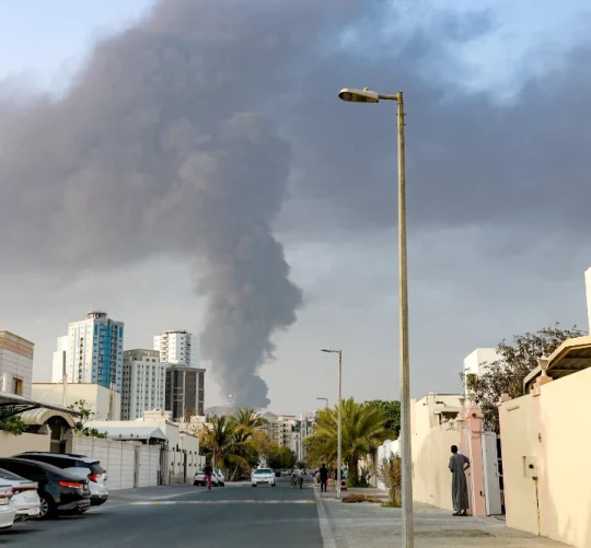 Люди спостерігають з вулиці, як високий стовп диму піднімається після вибуху в промисловій зоні Фуджейри в ОАЕ, 3 березня 2026 року