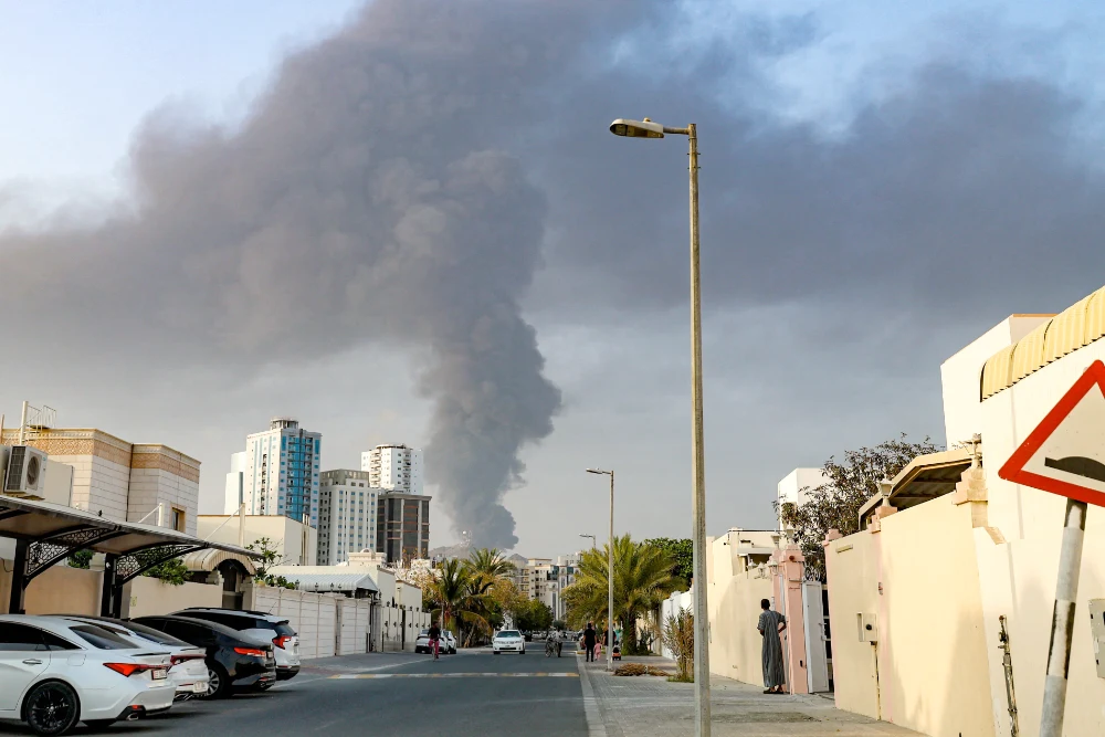 Люди спостерігають з вулиці, як високий стовп диму піднімається після вибуху в промисловій зоні Фуджейри в ОАЕ, 3 березня 2026 року
