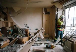 Рятувальники оглядають балкон пошкодженої квартири після удару дрона в Харкові