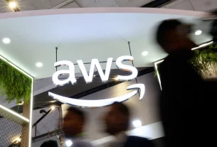 Люди проходять повз логотип Amazon Web Services (AWS) на стенді компанії на виставці India Mobile Congress 2025