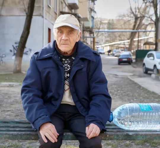 73-річний Валентин Беліський відпочиває на лавці перед тим, як піднятися сходами до своєї квартири на четвертому поверсі з каністрою води, яку він купив у місті Бєлці, Молдова, у вівторок, 17 березня 2026 року