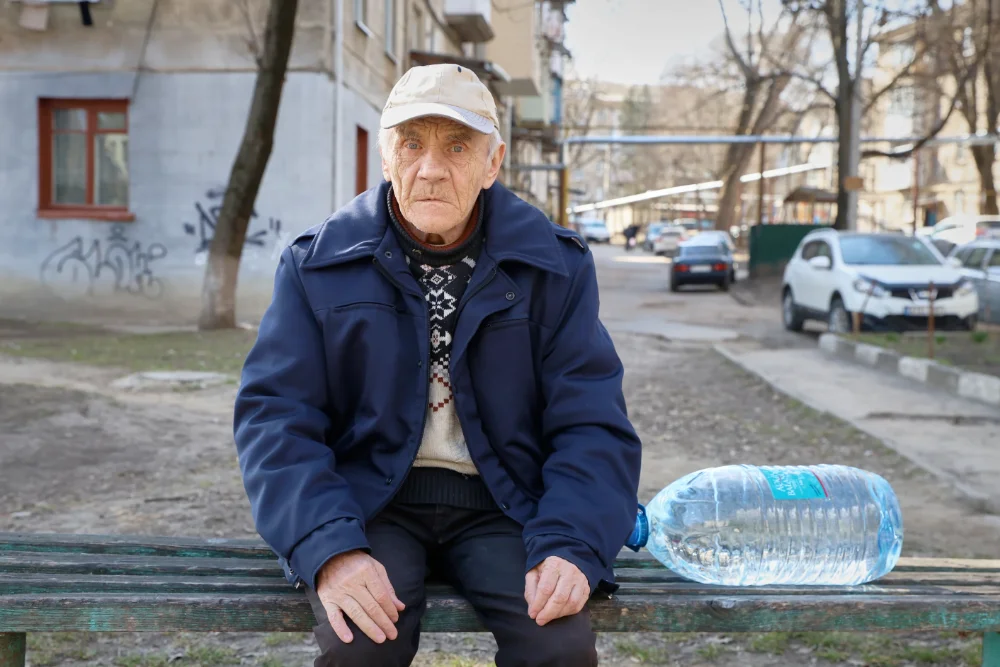 73-річний Валентин Беліський відпочиває на лавці перед тим, як піднятися сходами до своєї квартири на четвертому поверсі з каністрою води, яку він купив у місті Бєлці, Молдова, у вівторок, 17 березня 2026 року