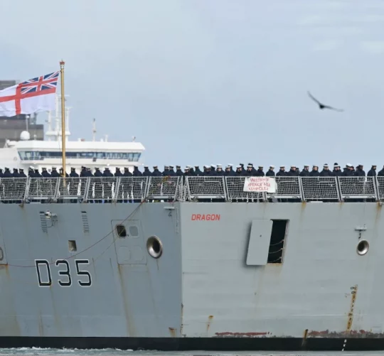 Члени екіпажу стоять на палубі HMS Dragon, який керується буксирами з військово-морської бази Портсмут на південному узбережжі Англії, 10 березня 2026 року