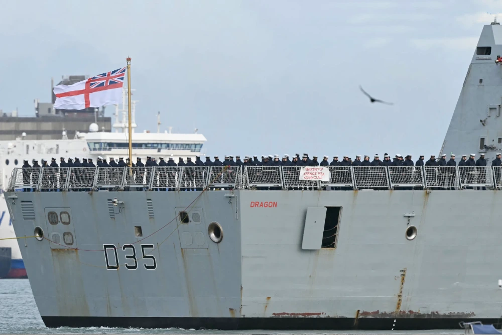 Члени екіпажу стоять на палубі HMS Dragon, який керується буксирами з військово-морської бази Портсмут на південному узбережжі Англії, 10 березня 2026 року