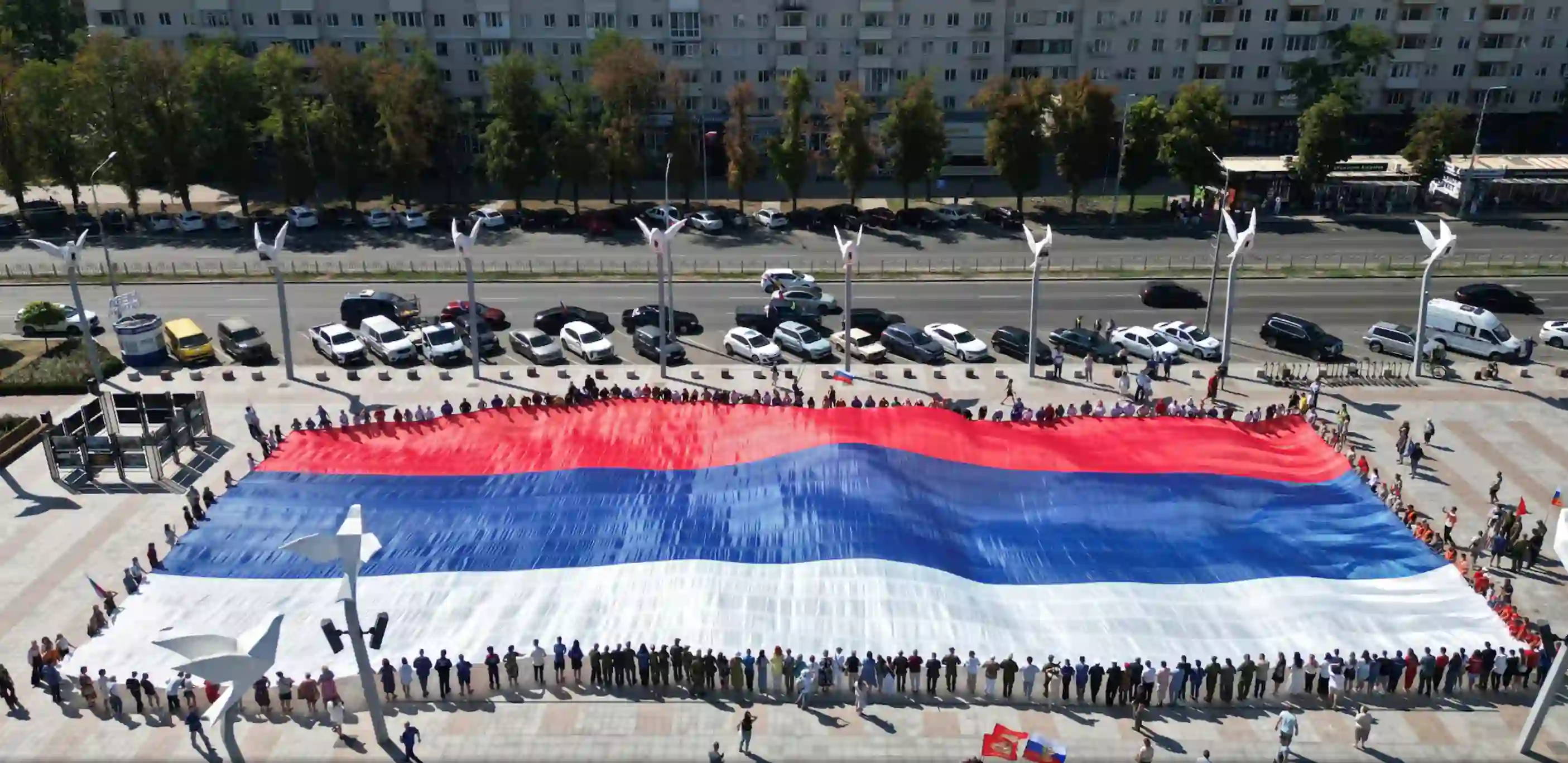 Величезний російський прапор піднятий десятками людей у окупованому українському портовому місті Маріуполь під час святкувань Дня національного прапора Росії в серпні минулого року