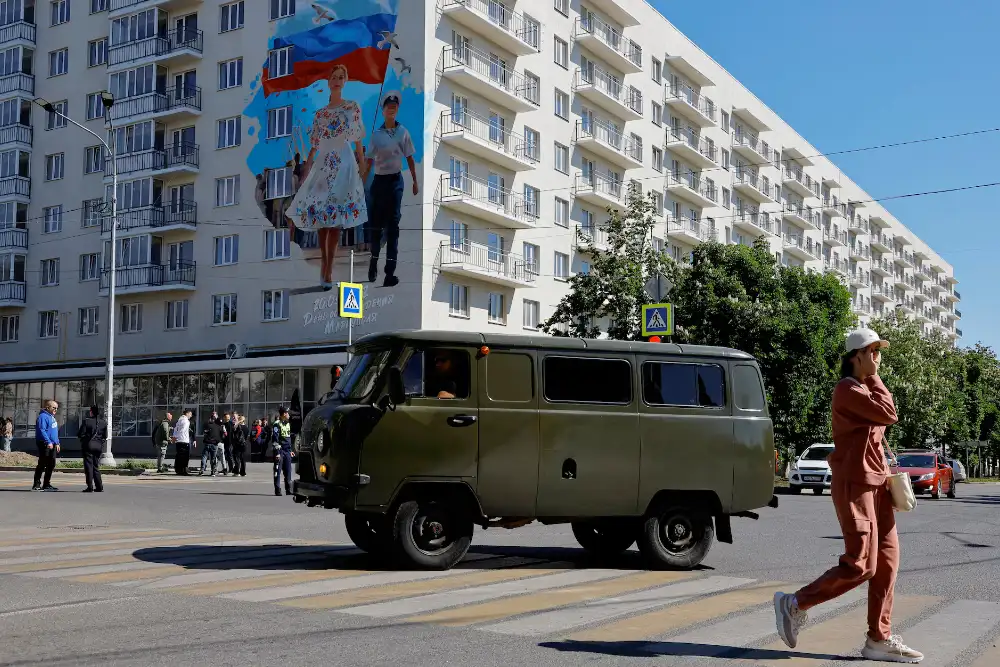 Мурал, розміщений на будівлі на честь третьої річниці взяття Росією під контроль над Маріуполем, височіє над мешканцями окупованого українського міста у травні 2025 року