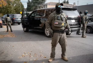 Федеральні агенти стоять на варті, коли їх зустрічають мешканці після зупинки під час поїздки в каравані через район Брайтон-Парк 6 листопада 2025 року в Чикаго, Іллінойс.