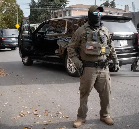 Федеральні агенти стоять на варті, коли їх зустрічають мешканці після зупинки під час поїздки в каравані через район Брайтон-Парк 6 листопада 2025 року в Чикаго, Іллінойс.