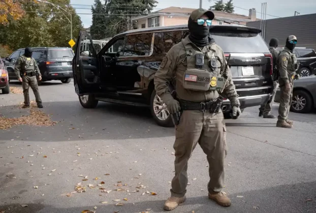 Федеральні агенти стоять на варті, коли їх зустрічають мешканці після зупинки під час поїздки в каравані через район Брайтон-Парк 6 листопада 2025 року в Чикаго, Іллінойс.