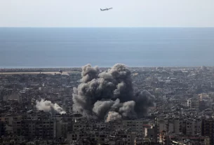 Літак летить, коли клуби диму піднімаються після ізраїльського удару по південних передмістях Бейрута після ескалації між "Хезболлою" та Ізраїлем на тлі американо-ізраїльського конфлікту з Іраном