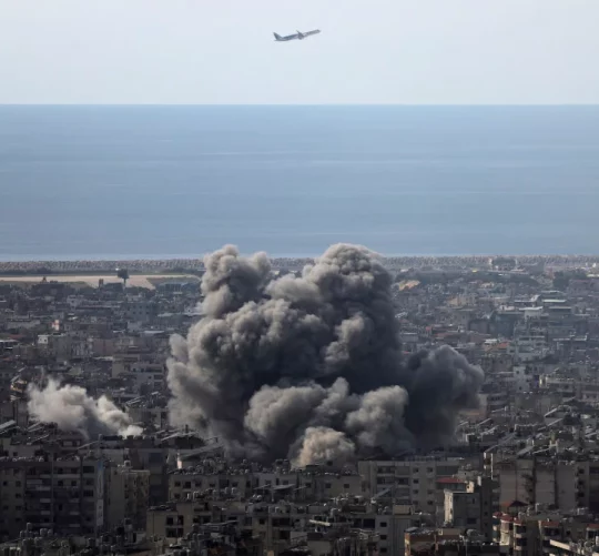Літак летить, коли клуби диму піднімаються після ізраїльського удару по південних передмістях Бейрута після ескалації між "Хезболлою" та Ізраїлем на тлі американо-ізраїльського конфлікту з Іраном