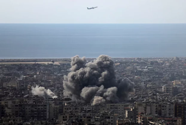 Літак летить, коли клуби диму піднімаються після ізраїльського удару по південних передмістях Бейрута після ескалації між "Хезболлою" та Ізраїлем на тлі американо-ізраїльського конфлікту з Іраном