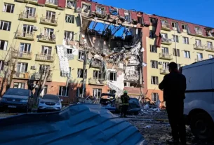 Рятувальник йде перед житловим будинком, який був сильно пошкоджений після російського удару в Одесі, Україна, 6 квітня 2026 року