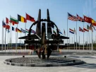У штаб-квартирі в Брюсселі видно емблему НАТО на фоні прапорів 32 країн-членів