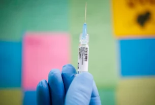 На цій ілюстративній фотографії, зробленій 24 вересня 2025 року в Швенксвіллі, штат Пенсильванія, США, людина позує з дозою вакцини Pfizer COMIRNATY (вакцина проти COVID-19, мРНК)