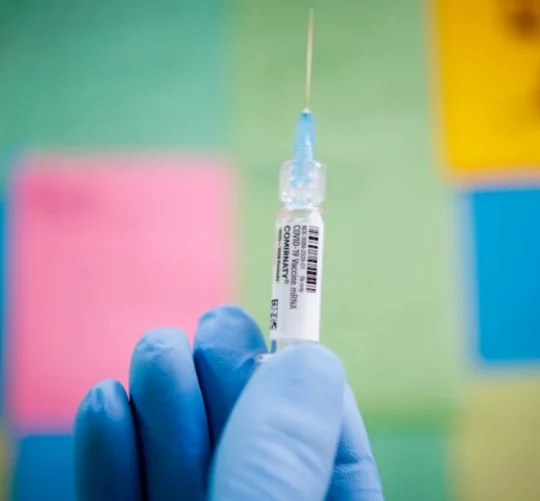 На цій ілюстративній фотографії, зробленій 24 вересня 2025 року в Швенксвіллі, штат Пенсильванія, США, людина позує з дозою вакцини Pfizer COMIRNATY (вакцина проти COVID-19, мРНК)