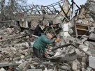 Двоє чоловіків розбирають залишки будинку, зруйнованого внаслідок російського авіаудару на околиці Запоріжжя