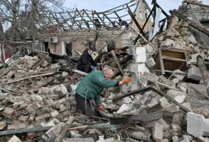 Двоє чоловіків розбирають залишки будинку, зруйнованого внаслідок російського авіаудару на околиці Запоріжжя