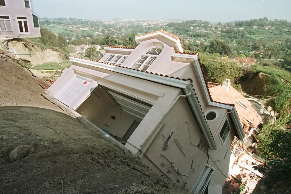 Розкішний будинок в окрузі Оранж у метрополітенській зоні Лос-Анджелеса зісковзує з еродованого схилу 19 березня 1998 року після сильних дощів, спричинених Ель-Ніньо на початку місяця