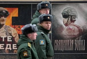 російські військові на фоні вивіски з рекламою "Священная война"