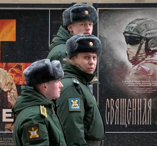 російські військові на фоні вивіски з рекламою "Священная война"
