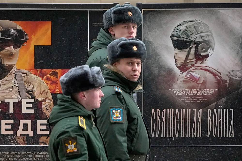 російські військові на фоні вивіски з рекламою "Священная война"