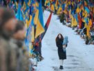 молода жінка йде з малюком на руках повз могили загиблих українських воїнів