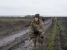 українська жінка військова йде по переду з автоматом по українському полі