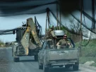 Українські військовослужбовці їздять у транспортних засобах дорогою, накритою сітками для захисту транспортних засобів від атак дронів