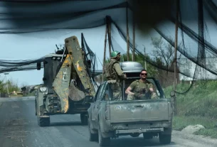 Українські військовослужбовці їздять у транспортних засобах дорогою, накритою сітками для захисту транспортних засобів від атак дронів