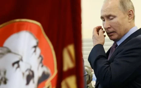 Володимир Путін проходить біля прапорів з фото Леніна та Сталіна