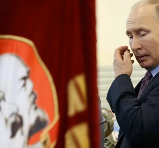 Володимир Путін проходить біля прапорів з фото Леніна та Сталіна