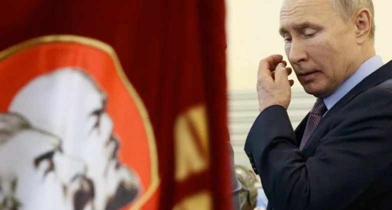 Володимир Путін проходить біля прапорів з фото Леніна та Сталіна