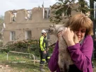 жінка тримає знайдену кошеня біля зруйнованого дому після російського обстрілу