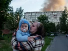 Мати тримає дитину біля ураженого обстрілом Росії житлового будинку